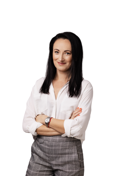 Kobieta stoi z założonymi rękami. Półdługie czarne proste włosy. Uśmiecha się
